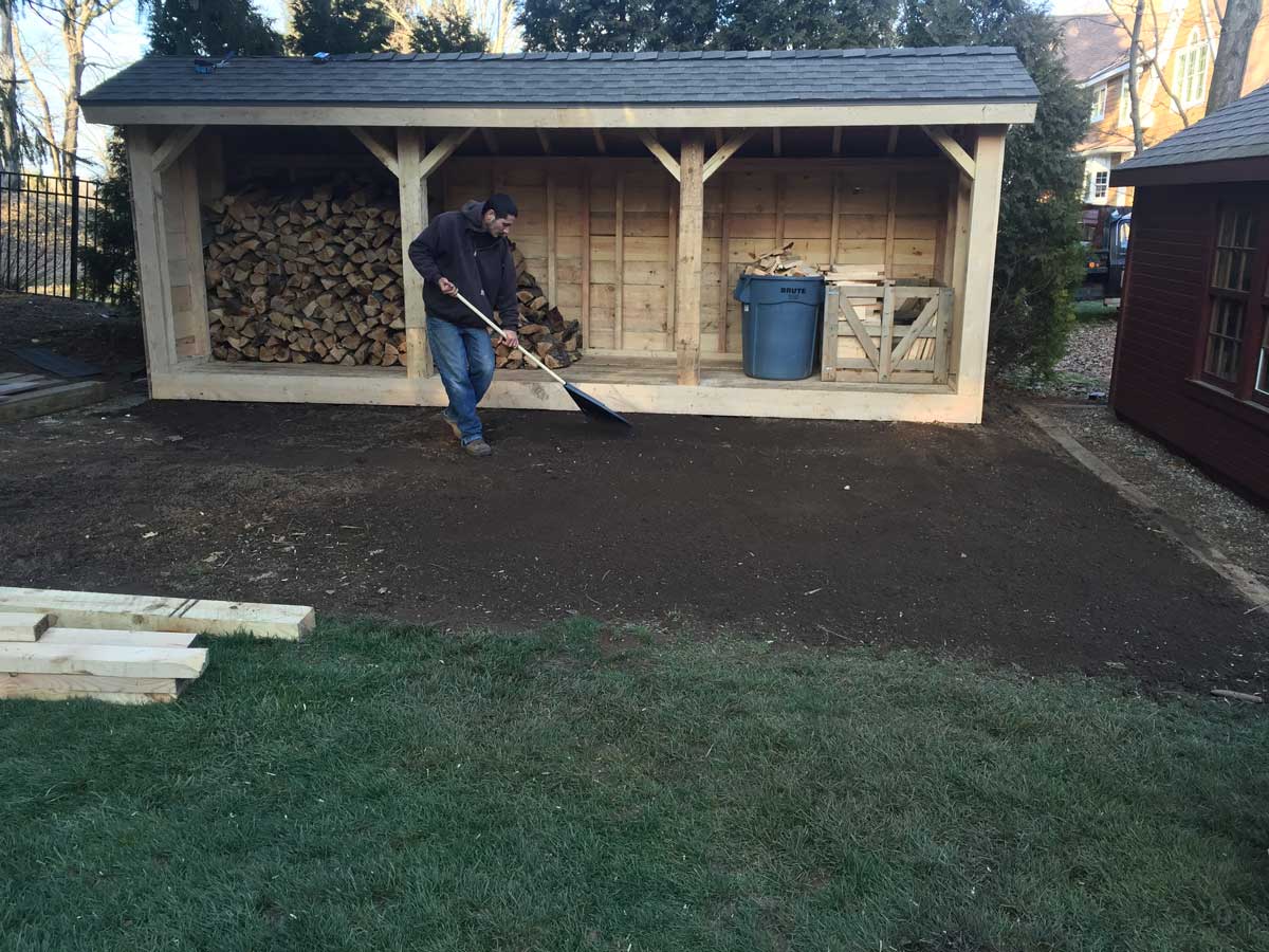 man raking dirt in backyard